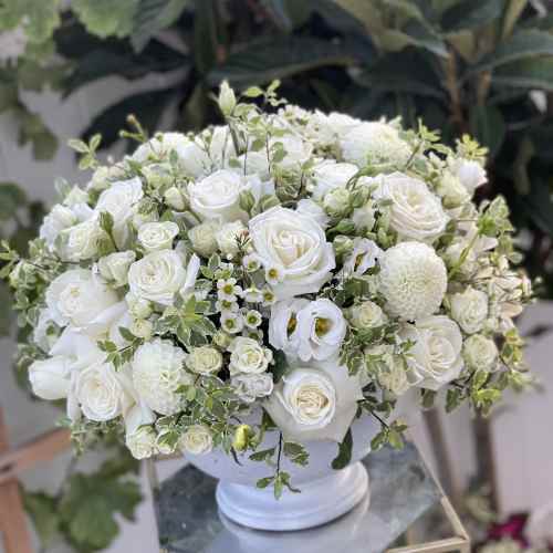 White rose and dahlia arrangement in a white vase