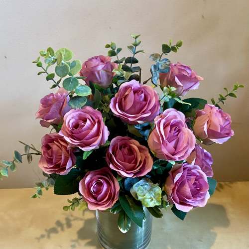 Pink roses arranged in a metal vase with eucalyptus