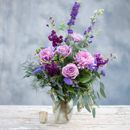 Lavender roses and purple flowers in a glass vase