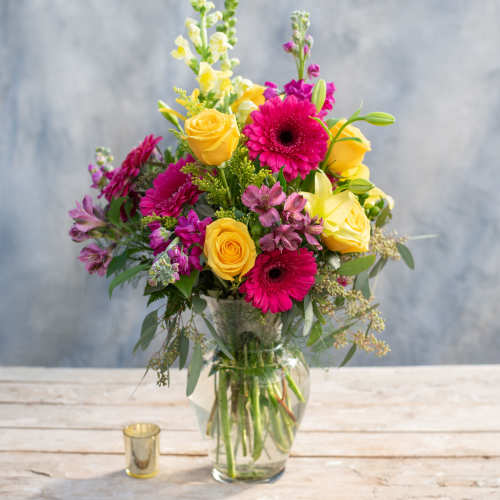 Bouquet of yellow roses and pink gerbera daisies in a glass vase