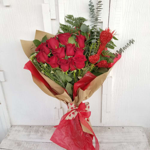 Bouquet of red roses wrapped in brown and red paper with a ribbon