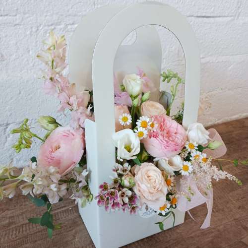Pastel flower arrangement in a white handled box with pink and white blooms