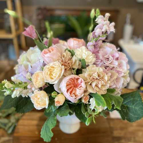 Pastel bouquet of roses, carnations, and hydrangeas in a white vase