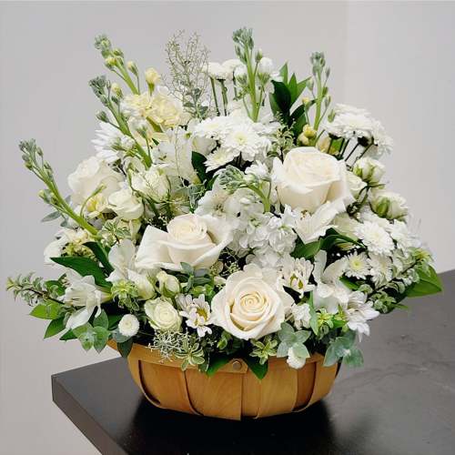 White roses and mixed white flowers in a woven basket