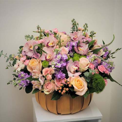Large pastel flower arrangement in a wooden basket