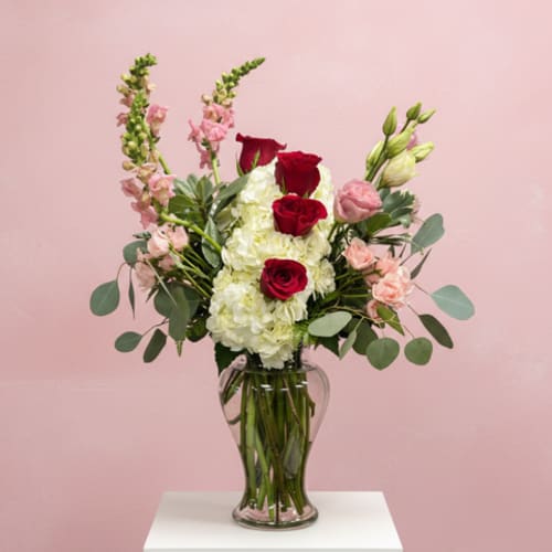 Red roses and white hydrangeas in a clear glass vase