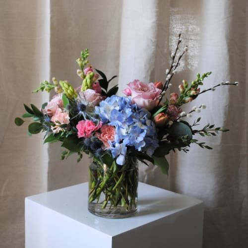 Pink and blue flower arrangement in a clear glass vase