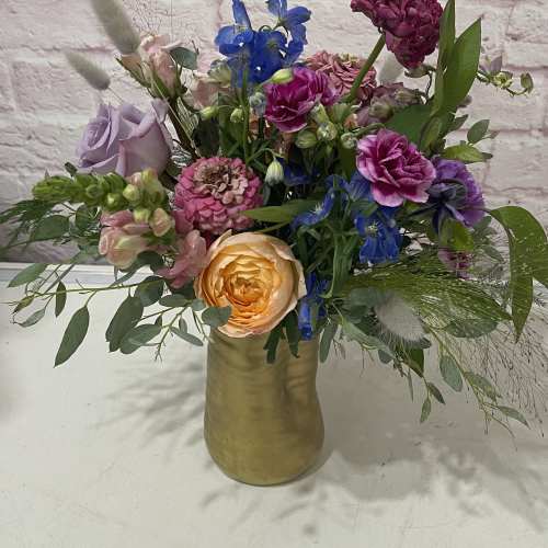 Mixed bouquet in a gold vase with roses and blue flowers