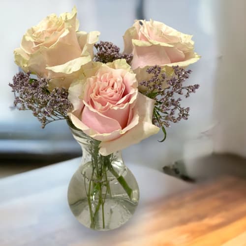 Pink roses and purple filler flowers in a clear glass vase