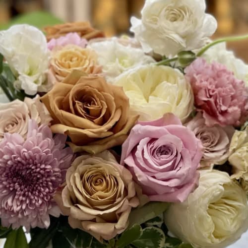 Lush arrangement of peach, blush, and cream roses mixed with mums and other soft blooms