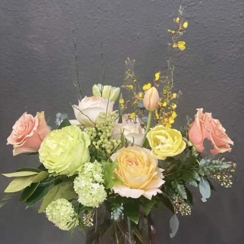 Mixed pastel roses and blooms arranged in a glass vase