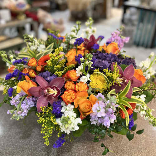 Colorful mixed bouquet with orange roses, purple orchids, and yellow accents