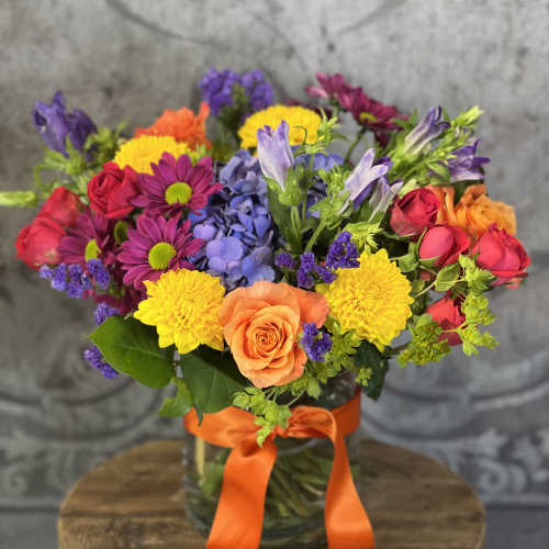 Colorful mixed bouquet in a glass vase with an orange ribbon