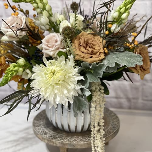 Mixed floral arrangement in a striped vase with white and tan blooms