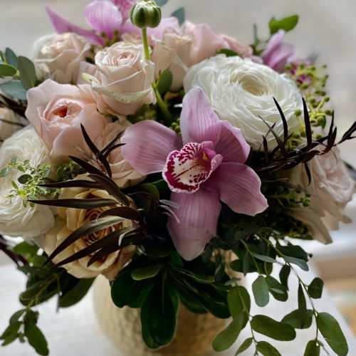 Pink and white floral bouquet with roses and orchids in a vase