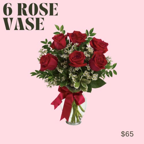 Six red roses in a clear glass vase with a red ribbon