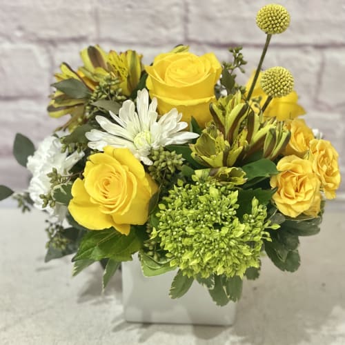 Yellow roses and white daisies in a white vase