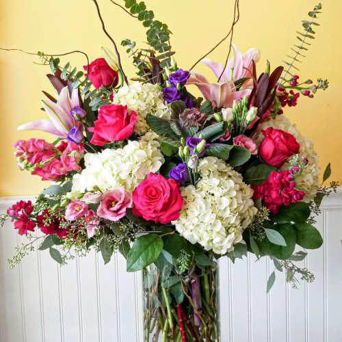Large mixed bouquet of pink, white, and purple flowers in a glass vase