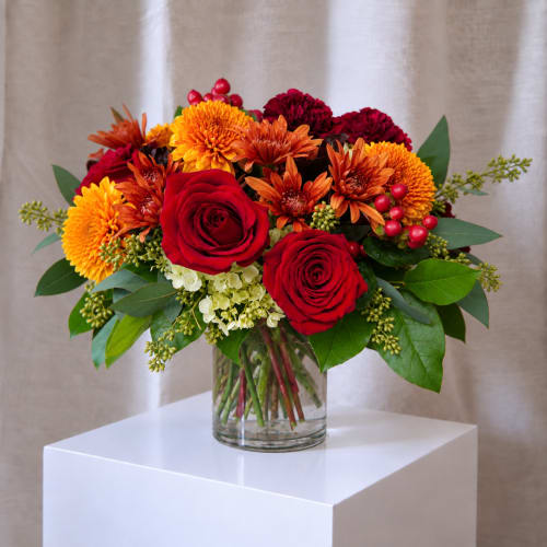 Red roses and orange mums in a clear glass vase