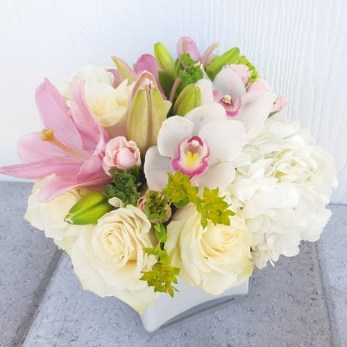 Bouquet of pink lilies, white roses, and white orchids in a white vase