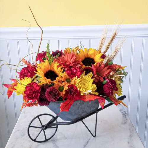 Colorful fall flower arrangement in a wheelbarrow-shaped container