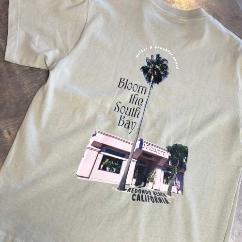 Light green T-shirt with a floral shop graphic and palm tree print