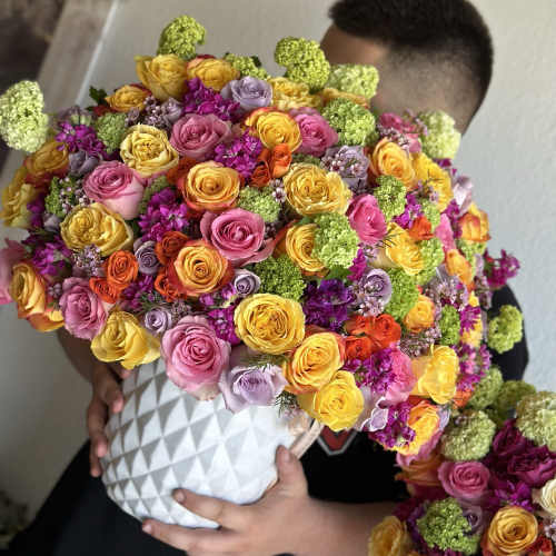 Large bouquet of multicolored roses in a white textured vase