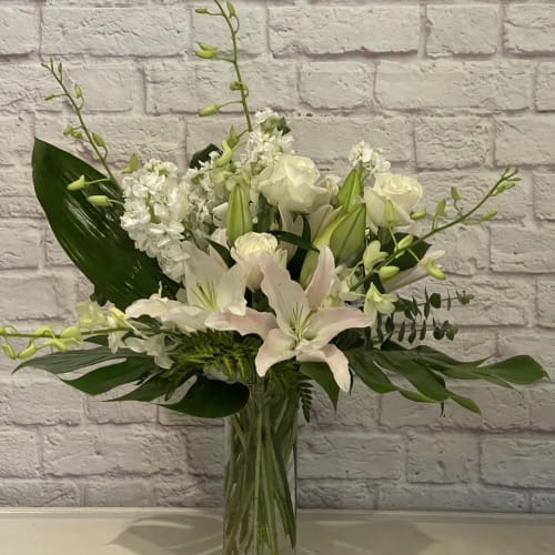 White lilies and roses arranged in a clear glass vase