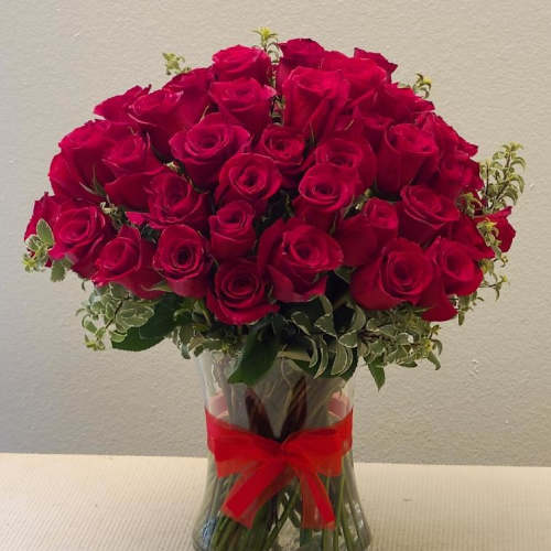 Bouquet of red roses in a clear glass vase with a red ribbon