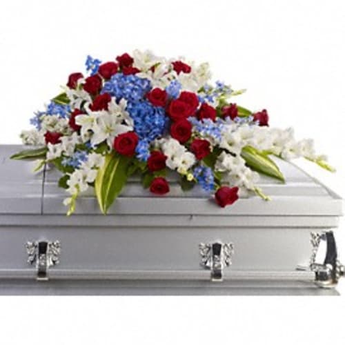 Red, white, and blue floral arrangement on a silver casket