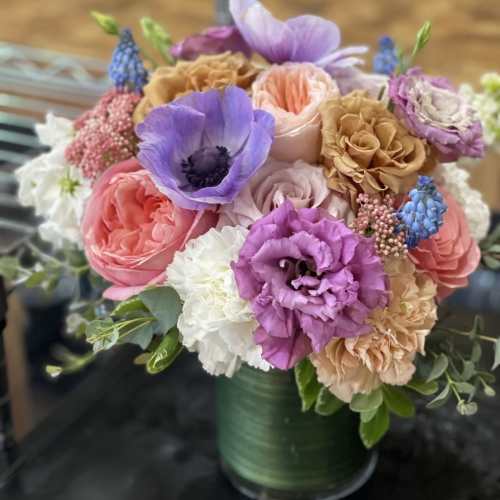 Mixed bouquet of pastel flowers in a green vase