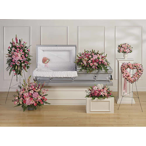 Pink floral funeral casket spray with matching arrangements and heart wreath