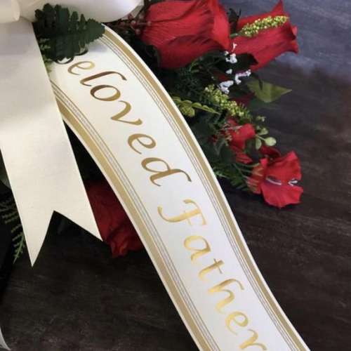 Red floral spray with a white ribbon reading "beloved father"