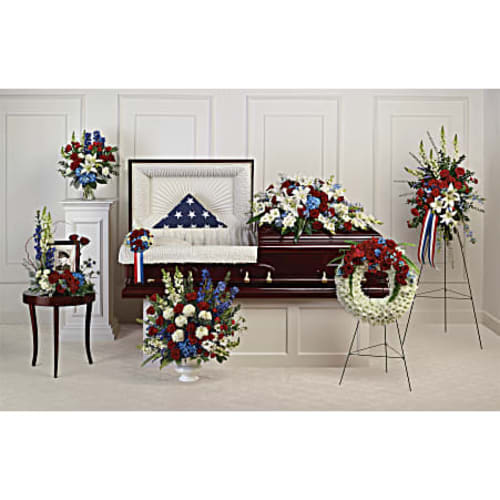Funeral casket spray and standing floral tributes in red, white, and blue