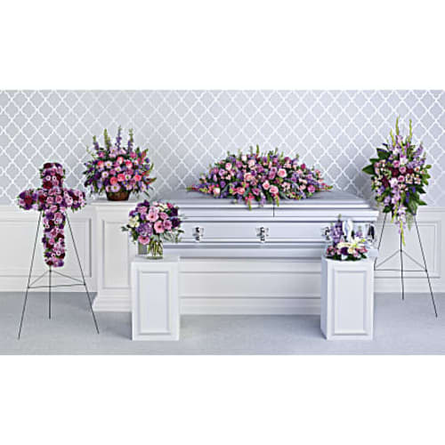 Funeral casket surrounded by pink and purple floral sprays