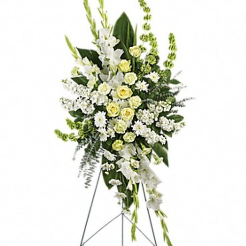 Tall white and pale yellow funeral spray on a metal stand