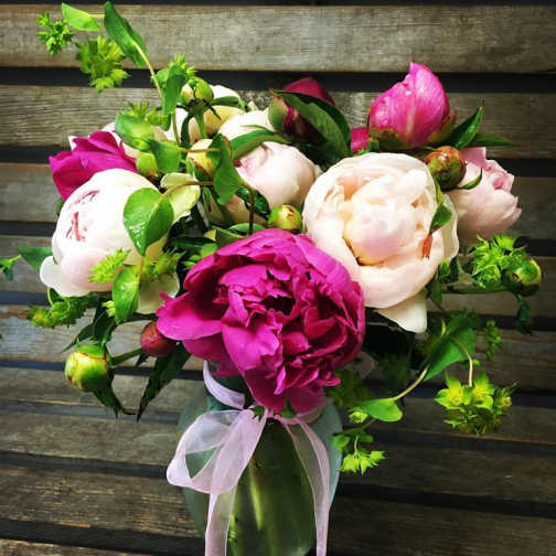 Bouquet of pink and white peonies in a glass vase with a ribbon