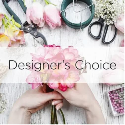 Hands arranging pink flowers with floral tools on a white table