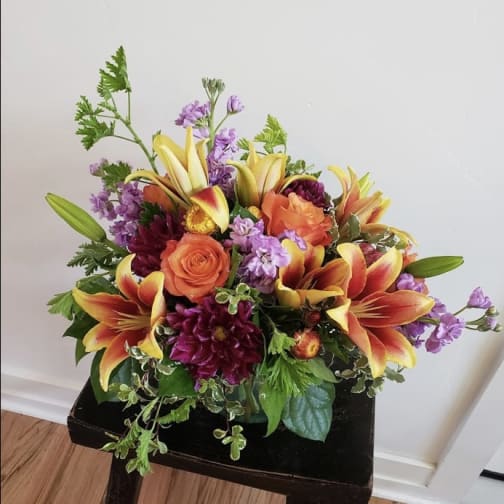 Bouquet of orange roses, lilies, and purple flowers