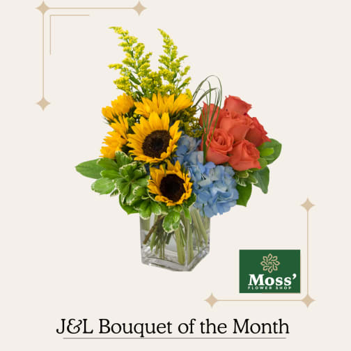 Bouquet of sunflowers, coral roses, and blue hydrangeas in a glass vase