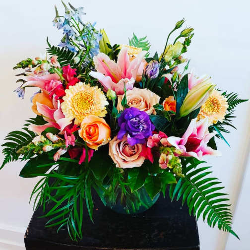 Colorful mixed bouquet in a round vase with lilies and roses