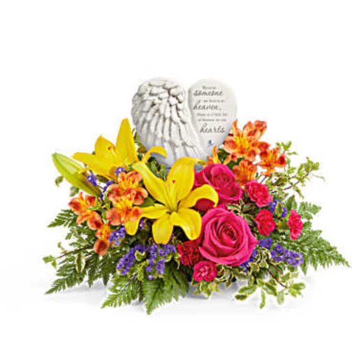 Bright mixed bouquet with yellow lilies, pink roses, and orange alstroemeria around a memorial stone