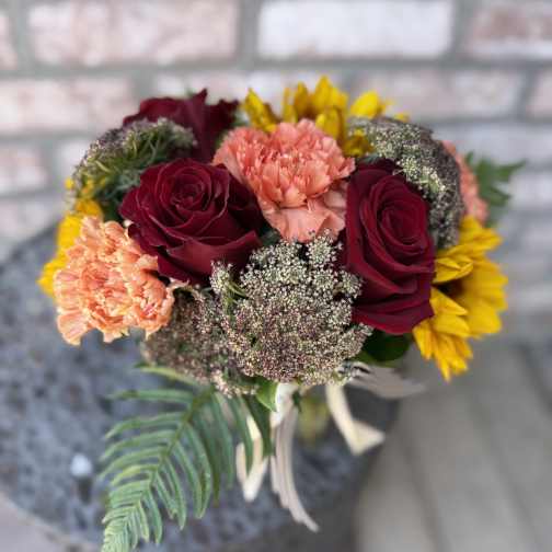 Bouquet of burgundy roses, peach carnations, and yellow flowers