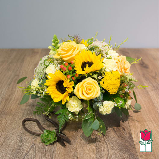 Yellow roses and sunflowers in a low glass vase with a ribboned succulent accent