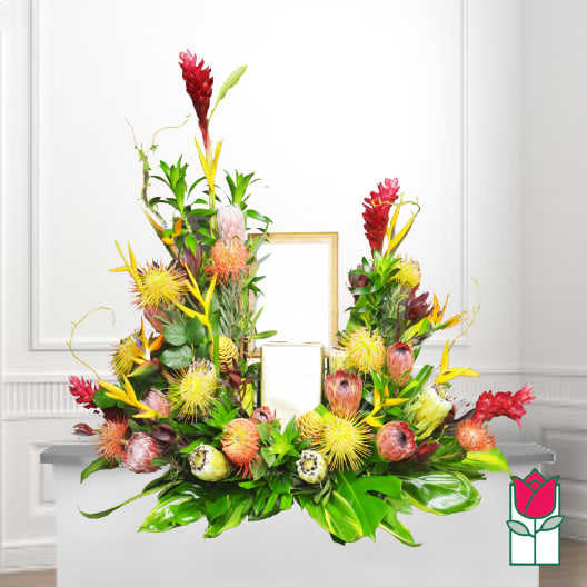 Tropical floral arrangement with red and yellow blooms around a candle