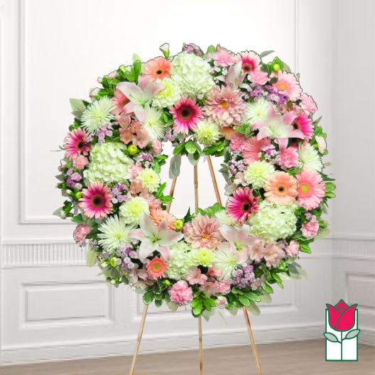 Large floral wreath on a stand with pink, white, and green flowers