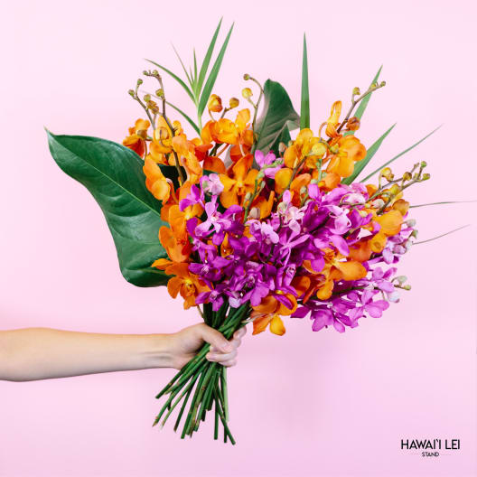 Handheld bouquet of orange and purple orchids against a pink background