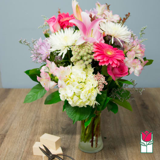 Mixed pink and white flowers in a glass vase on a table