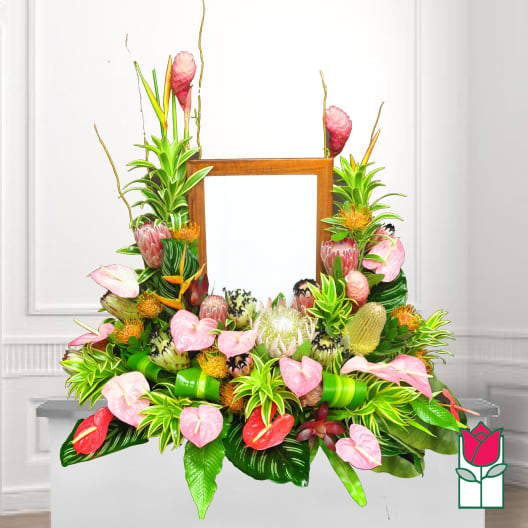 Tropical floral arrangement with pink anthuriums and protea around a wooden frame