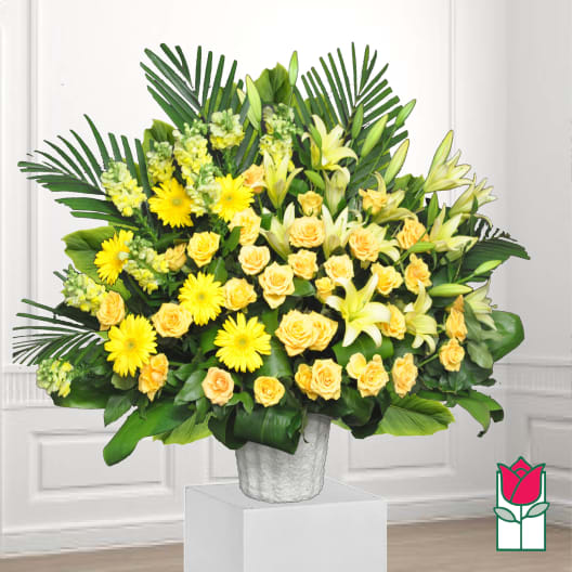 Yellow roses and lilies arranged in a white vase